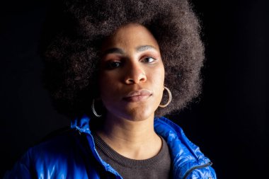 Afro-Amerikan kadın, karışık ırk, karanlık arka planda poz, şehir kıyafetleri, modern güzel ve gülümseyen.