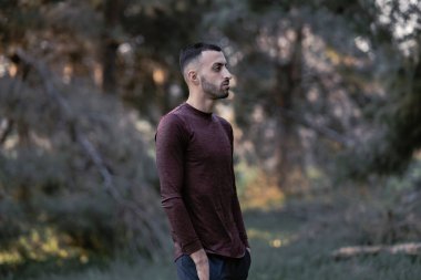 Gündelik giysiler içinde yakışıklı bir genç ve ormanda orman yürüyüşü yapan bir turist.