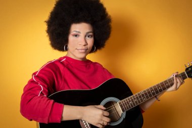 Stüdyoda gitar çalan sevimli Afrikalı Amerikalı kadın.