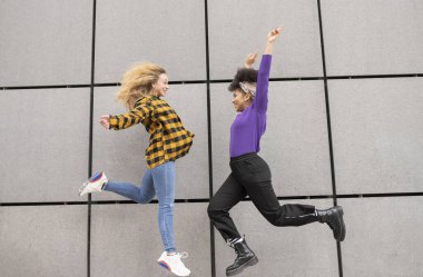 İki mutlu melez kadın sokakta zıplıyor.