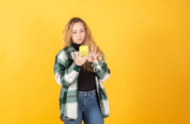 Güzel sarışın kadın akıllı telefon kullanıyor mutlu, sarı arka plan gülümsüyor