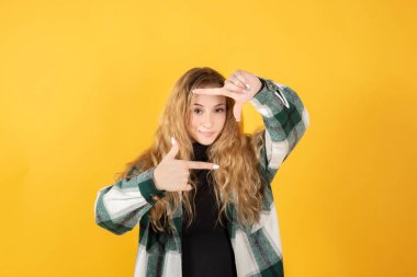 Güzel sarışın kadın hayali bir kamera sarı arka planıyla fotoğraf çekiyor.