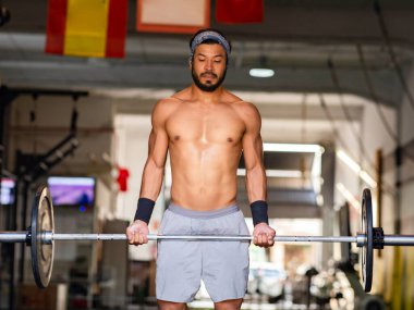 Adam spor salonunda ağırlık kaldırıyor.