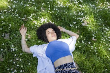 Parkta çiçeklerle çimenlerin üzerinde uzanan güzel bir kadın.