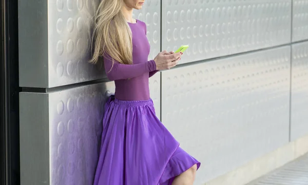 紫のバレエの服を着た金髪の女性がスマートフォンを使って — ストック写真