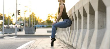 Günlük giysiler içinde sanatçı kadın dansçı şehir trafiğiyle çevrili sokaklarda mutlu ve özgürce gösteri yapıyor.