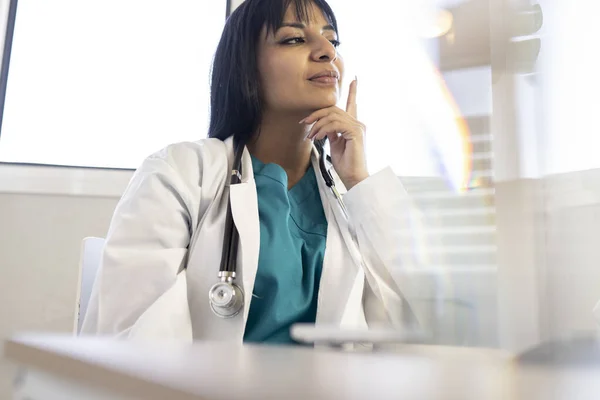 Young Latina doctor, in a medical consultation, serious thoughtful,