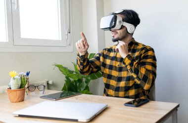 Sanal gerçeklik gözlüklü bir adam ofiste oturup el hareketi yapıyor.