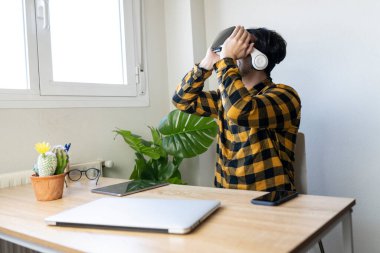 Oturan adam merkez ofiste sanal gerçeklik gözlükleriyle çalışıyor.