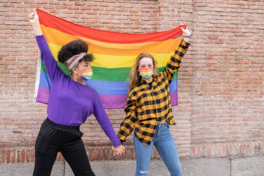 iki güzel Afrikalı ve beyaz kadın, gay gurur bayrağıyla