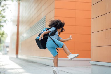 Sırt çantası, anaokulu, yakışıklı, kıvırcık saçlı çocukla sınıftan atlayan mutlu çocuk.