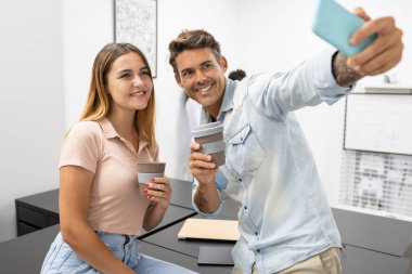 Birkaç ofis çalışanı kahve içerken selfie çekiyorlar.