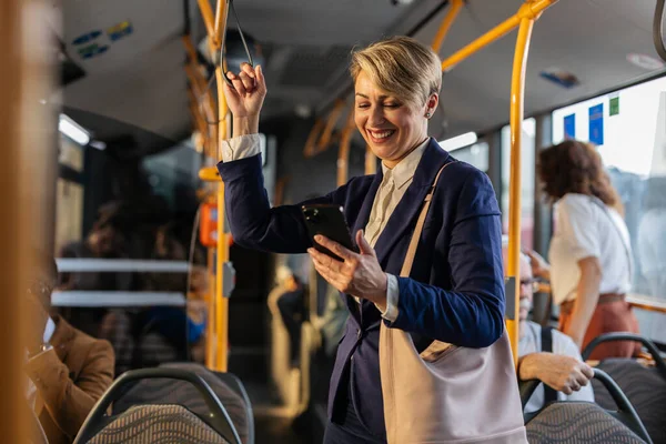 Profesyonel bir iş adamı işe gidip gelirken ya da gelirken cep telefonundaki mesajları neşeyle kontrol ederken tırabzana tutunuyor.