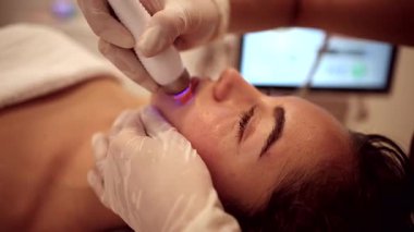 Young woman relaxing during a non invasive radiofrequency lifting procedure performed by a professional cosmetologist to rejuvenate her skin and reduce wrinkles in a modern beauty clinic