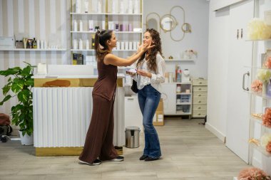 Güzellik salonunda bir müşterinin cildini ve yüzünü inceleyen estetisyen, kişiselleştirilmiş cilt bakımı seçenekleri ve profesyonel bir perakende ortamında ürün tavsiyelerini tartışıyor