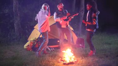 Neşeli çoklu etnik gruptan arkadaşlar, açık havada bir yaz gecesinin tadını çıkarıyorlar. Bir adam ormanda çadırlarının yanında çadır kurup gitar çalarken birlikte dans edip şarkı söylüyorlar.