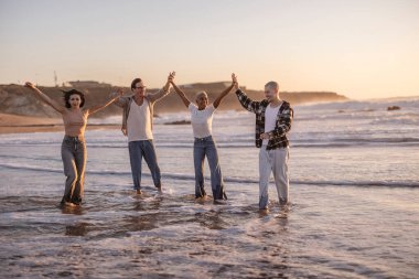 Çeşitli arkadaşlar birleşir, el ele tutuşur ve kutlamak için kollarını kaldırır. Gün batımında okyanusta sörf yaparken, birlik, mutluluk ve yaz özgürlüğünü simgeler.