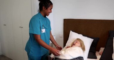 Genç bir bakıcı, huzurevinde sabah egzersizlerinde mutlu bir yaşlı kadına yardım ediyor. Yaşlı bir hastaya destek ve fizik tedavi sağlayan sağlık uzmanı