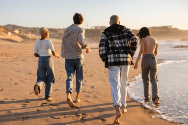 Çeşitli yetişkin arkadaş grupları kumlu sahil boyunca kaygısız bir gezinti yapıyorlar. Sıcak, altın saat gün batımında okyanus dalgalarını izliyorlar. Arkadaşlık ve özgürlük gösteriyorlar.