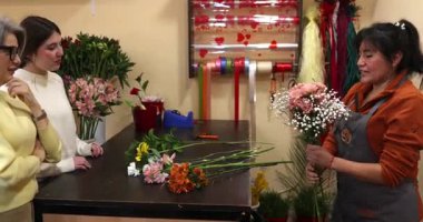 Deneyimli bir çiçekçi tezgahtaki mükemmel çiçekleri seçerek rahat atölyesinde güzel, özel bir çiçek aranjmanı yaratıyor.