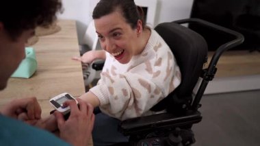 Erkek bakıcı, engelli bir kadının kan basıncını kontrol ediyor. Motorlu sandalyede oturuyor, bir anlık olumlu sağlık hizmeti ve yaşam desteği alıyor.