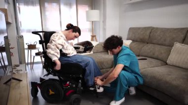 Erkek hemşire, tekerlekli sandalyedeki engelli bir kadına evde sanal gerçeklikte yardım ediyor. Gelişmiş tıp teknolojisi hastalara eğlence ve tedavi desteği sağlıyor