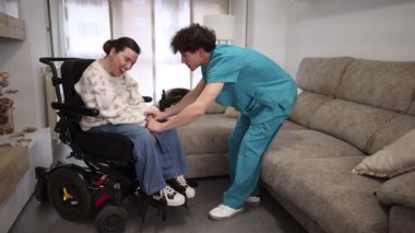 Erkek hemşire, tekerlekli sandalyedeki engelli bir kadına evde sanal gerçeklikte yardım ediyor. Gelişmiş tıp teknolojisi hastalara eğlence ve tedavi desteği sağlıyor