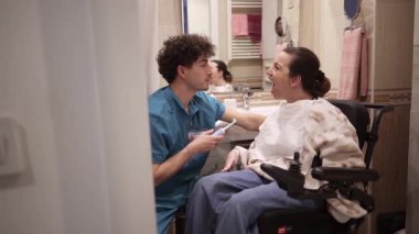 Erkek hemşire, tekerlekli sandalyedeki engelli bir kadına evde sanal gerçeklikte yardım ediyor. Gelişmiş tıp teknolojisi hastalara eğlence ve tedavi desteği sağlıyor