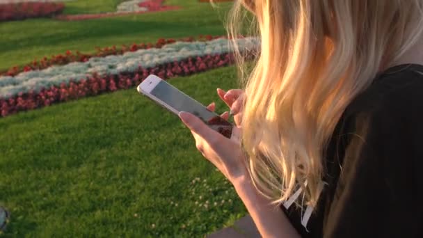 Ρωσία, Μόσχα - 23 Ιουλίου 2016: Η όμορφη ξανθιά με iphones ξεφυλλίζει φωτογραφίες στο πάρκο Vdnkh — Αρχείο Βίντεο