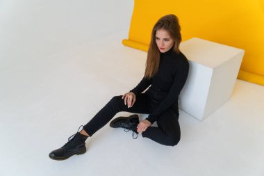 Uzun saçlı esmer bir kadın. Boş siyah bir kazak giyiyor.