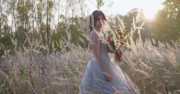 Una joven vestida con un vestido de novia gris. Tiene flores en la mano y está en el parque.. — Vídeos de Stock