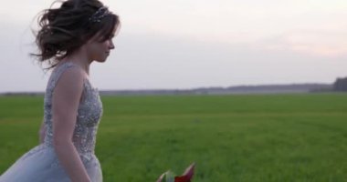 Gri gelinlik giymiş genç bir kadın düğününü kutluyor. Elinde çiçekler var ve şu an parkta..