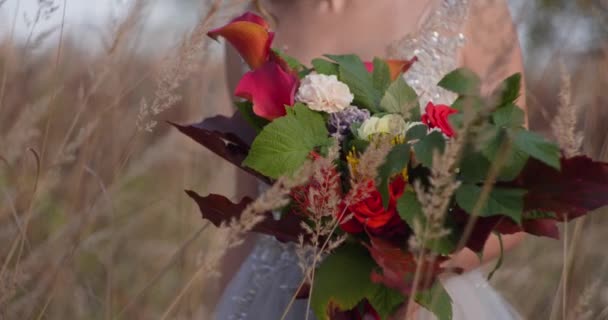 Gri gelinlik giymiş genç bir kadın düğününü kutluyor. Elinde çiçekler var ve şu an parkta.. — Stok video