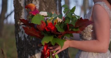 Gri elbiseli bir gelin ormanda bir buketle yürüyor..