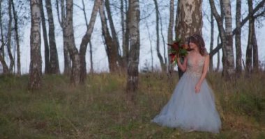 Gri elbiseli bir gelin ormanda bir buketle yürüyor..