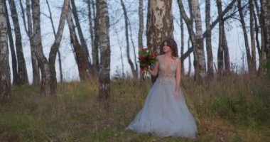 Gri elbiseli bir gelin ormanda bir buketle yürüyor..