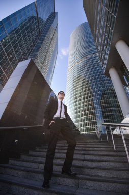 Gökdelenler tarafından çevrili bir merdiven üzerinde duran işadamı.