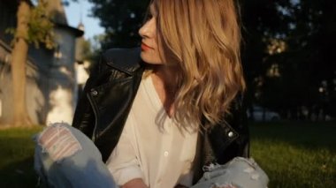 Kız model çimenlerin üzerine oturmuş poz.