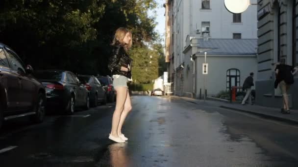 Όμορφο κορίτσι στο σορτς περπάτημα στο δρόμο μετά από μια βροχή. — Αρχείο Βίντεο