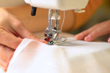 Beyaz kumaştan örülmüş perdelerin dikilme süreci. Görüntüyü kapat.