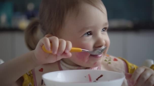 Söt barnmat. Baby flicka äter hälsosam mat själv. — Stockvideo