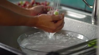Bir kadın kevgirle böğürtlen yıkıyor. Beyaz ve kırmızı üzümlü. Görüntüyü kapat