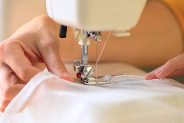 Beyaz kumaştan örülmüş perdelerin dikilme süreci. Görüntüyü kapat.