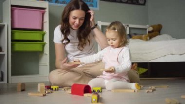 Anne ve kızı evde oyuncaklarla oynuyorlar. Anne küçük kızına yardım ediyor. Aile yaşam tarzı konsepti