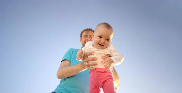 Zbliżenie uśmiechniętego dziecka w ramionach młodego ojca na niebieskim tle — Zdjęcie stockowe