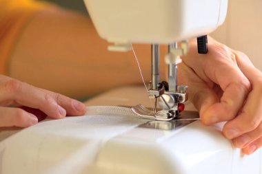 Beyaz kumaştan örülmüş perdelerin dikilme süreci. Görüntüyü kapat.