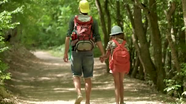 Man with backpack walking with girl at road in mountains. Travel lifestyle concept adventure outdoor summer vacations. Happy family hiking in the countryside — Stock Video