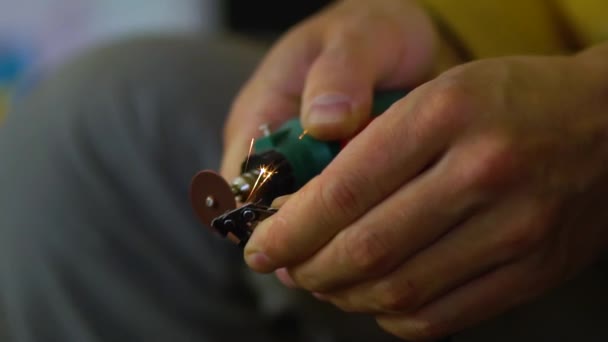 Gros plan sur la scie électrique et les mains du travailleur avec des étincelles. Homme travaillant avec une petite meuleuse, affûtage de la scie — Video