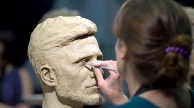 Kadın heykeltraş, insan kafası heykeli üzerinde çalışıyor..