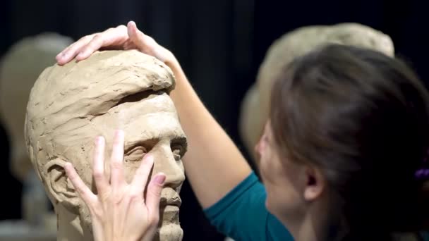 Mujer en proceso de creación de una escultura de una cabeza humana. Escultor trabajando. — Vídeo de stock